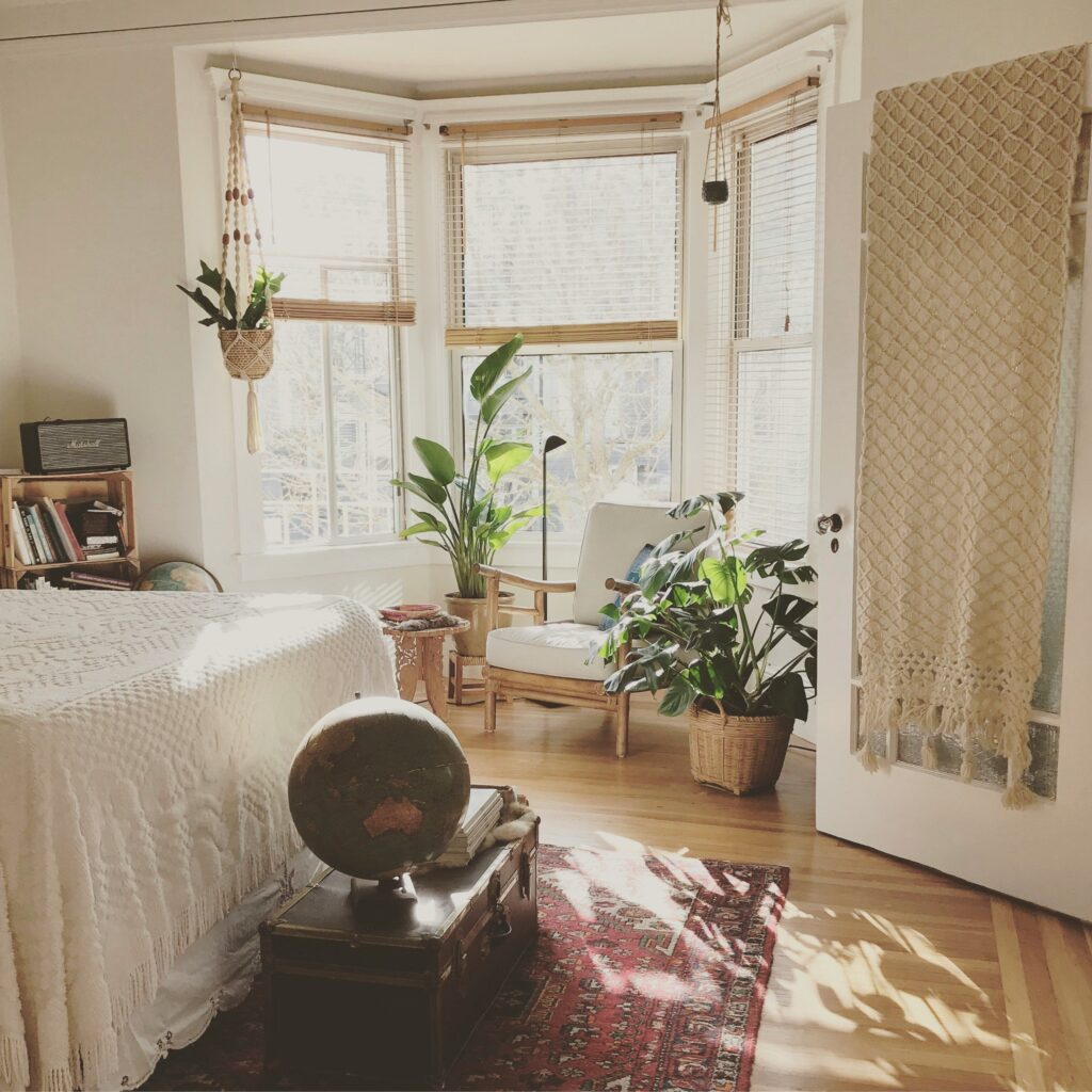 chambre adulte avec une décoration naturelle : meuble en bois, chaise en bois, plantes au sol et dans des pots suspendu